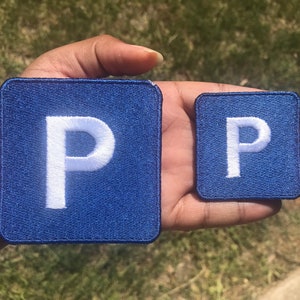 May include: Two blue fabric patches with a white letter "P" embroidered on each. The patches are different sizes.