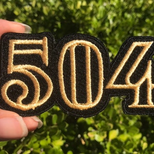 May include: A black fabric patch with the numbers 504 embroidered in gold thread.