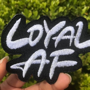 Peut inclure: Patch brod&eacute; blanc sur fond noir avec les mots "LOYAL AF" dans une police de style graffiti.