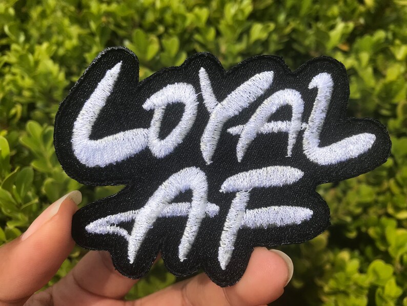 Peut inclure: Patch brod&eacute; blanc sur fond noir avec les mots "LOYAL AF" dans une police de style graffiti.