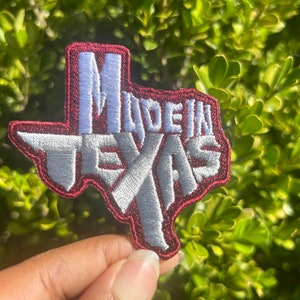 Peut inclure: Un patch brodé en forme de l'état du Texas avec les mots "Made in Texas" écrits à l'intérieur en rouge et blanc.