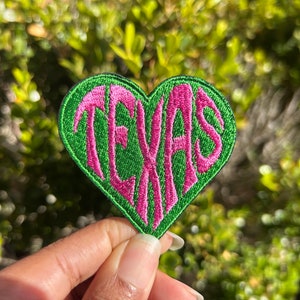 May include: Green heart-shaped patch with the word "TEXAS" embroidered in pink.