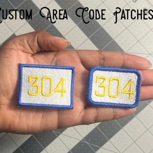 May include: Two white embroidered patches with a blue border. The patches have the number 304 in yellow thread.