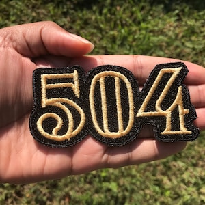 May include: Black and gold embroidered patch with the number 504.