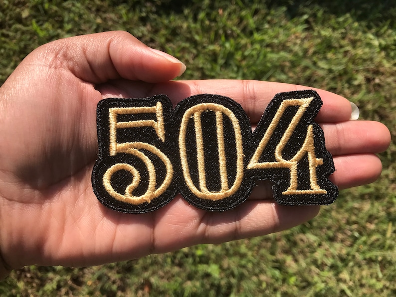 May include: Black and gold embroidered patch with the number 504.
