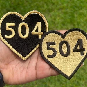 May include: Two heart-shaped embroidered patches. One is black with gold-colored stitching and the number "504". The other is gold with black stitching and the number "504". Both patches have a gold border.