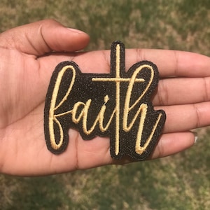 May include: A black fabric patch with the word "faith" embroidered in gold thread. A gold cross is also embroidered on the patch.