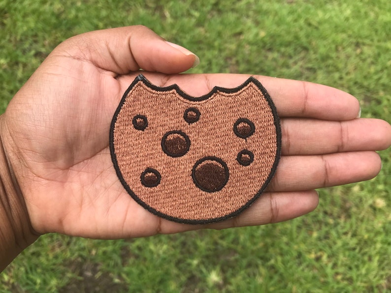 May include: A brown and black embroidered cookie patch with chocolate chips.