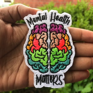 May include: A white embroidered patch with a colorful brain design and the text "Mental Health Matters".