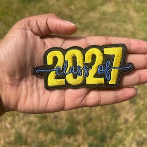 May include: Yellow embroidered patch with the text "Class of 2027" in blue thread.