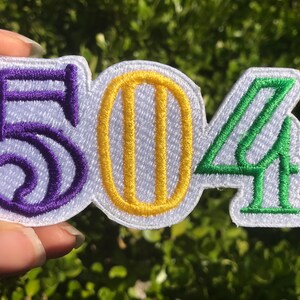 May include: Purple, yellow, and green embroidered patch with the numbers "504" on a white background.