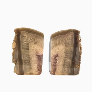 May include: A pair of agate bookends, each with a unique brown and white pattern. The bookends are made of natural agate and have a polished finish.