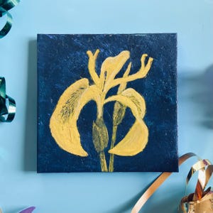 May include: A square canvas artwork depicting a yellow iris flower on a dark blue background. The flower's petals and stem are painted with visible brushstrokes. The artwork is a close-up of the flower.