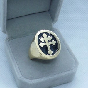 May include: A gold ring with a black enamel cross design. The ring is in a velvet ring box.