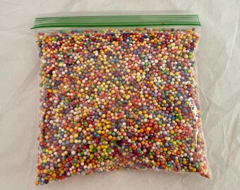 May include: A clear plastic bag filled with colorful, round, foam beads. The beads are a variety of colors, including red, orange, yellow, green, blue, purple, and white.