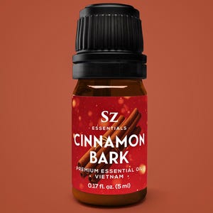 May include: A small brown glass bottle with a black cap, labeled "CINNAMON BARK" with cinnamon sticks graphic. The label also reads "PREMIUM ESSENTIAL OIL" and "0.17 fl. oz. (5 ml)".