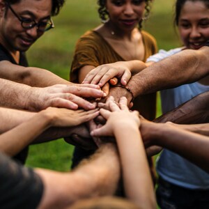 K&ouml;nnte beinhalten: Eine Gruppe von Menschen mit ihren H&auml;nden &uuml;bereinander gestapelt, symbolisiert Teamwork und Einheit.