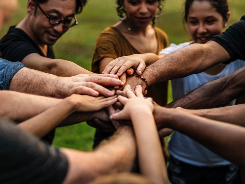 K&ouml;nnte beinhalten: Eine Gruppe von Menschen mit ihren H&auml;nden &uuml;bereinander gestapelt, symbolisiert Teamwork und Einheit.