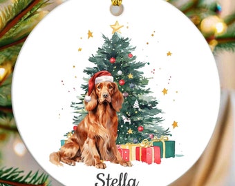 May include: White ceramic Christmas ornament featuring a watercolor illustration of a Cocker Spaniel wearing a Santa hat, in front of a decorated Christmas tree. The dog's name, "Stella", is written below. Gold hanging cord.