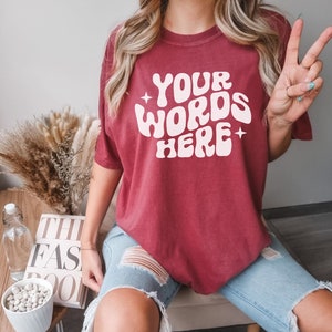 May include: A maroon t-shirt with the text "YOUR WORDS HERE" in a retro, white font.