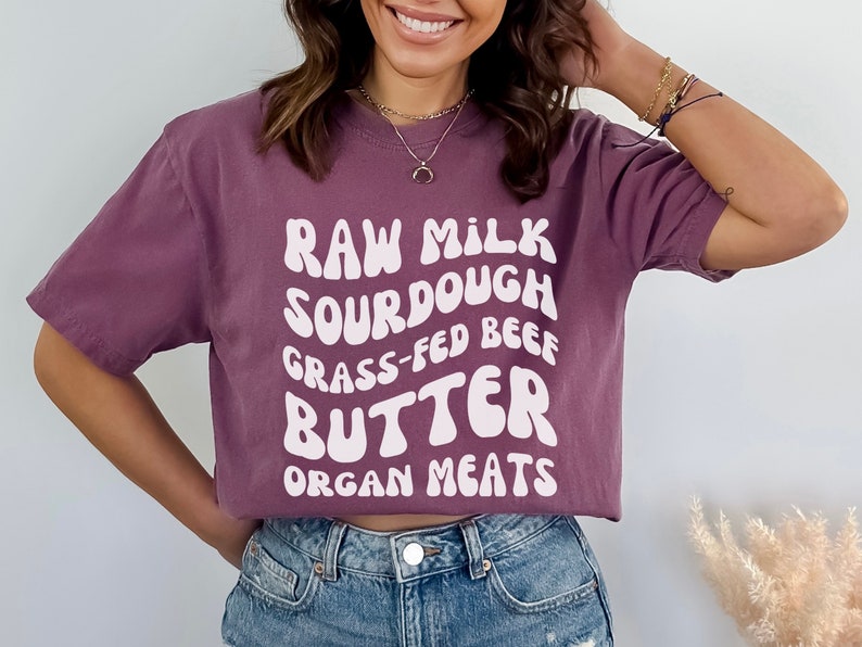 May include: A purple cropped t-shirt with white text that reads "Raw Milk Sourdough Grass-Fed Beef Butter Organ Meats".