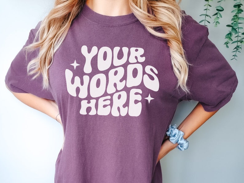 May include: A purple t-shirt with the text "YOUR WORDS HERE" in a retro, white font.
