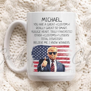 May include: White ceramic mug with a handle. The mug has a red, white, and blue American flag design with a cartoon image of a man wearing a suit and sunglasses. The text on the mug reads "MICHAEL, YOU ARE A GREAT <CUSTOM>! REALLY GREAT! SO SMART. YUUUGE HEART. TRULY FANTASTIC! OTHER <CUSTOMS>? LOSERS! TOTAL DISASTERS! BELIEVE ME, I KNOW WINNERS."