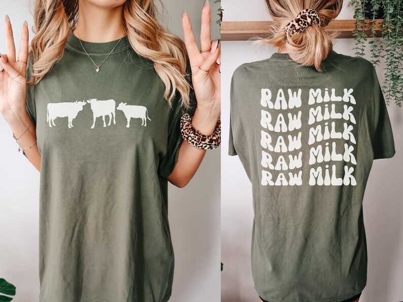 May include: A green t-shirt with a white silhouette of three cows on the front and the text "RAW MILK" repeated five times on the back.