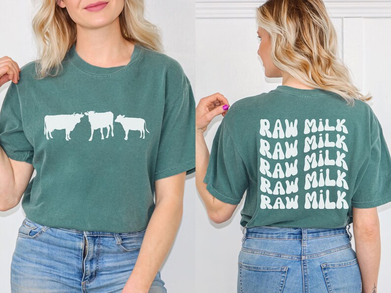 May include: A teal green t-shirt with a white silhouette of three cows on the front and the text "RAW MILK" repeated five times on the back.