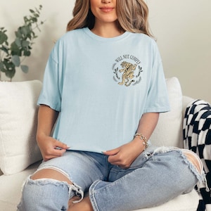 May include: A light blue t-shirt with a graphic of a tiger and the text "Will Not Comply".