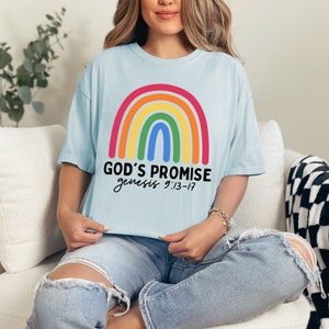 K&ouml;nnte beinhalten: Ein hellblaues T-Shirt mit einem Regenbogen-Motiv und dem Text "GOD'S PROMISE genesis 9:13-17".