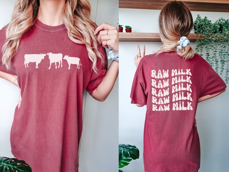 May include: A maroon t-shirt with a white silhouette of three cows on the front and the text "RAW MILK" repeated five times on the back.