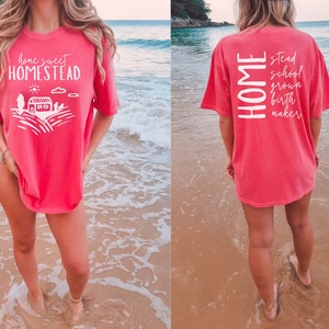 May include: A pink t-shirt with the text "home sweet homestead" on the front and "HOME stead school grown birth maker" on the back.