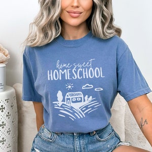 May include: A blue t-shirt with the text "home sweet HOMESCHOOL" in white. The shirt features a white illustration of a house with a sun and clouds.