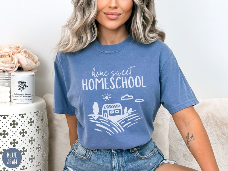May include: A blue t-shirt with the text "home sweet HOMESCHOOL" in white. The shirt features a white illustration of a house with a sun and clouds.