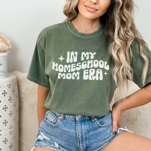 May include: A green t-shirt with the text "In My Homeschool Mom Era" in a retro font.