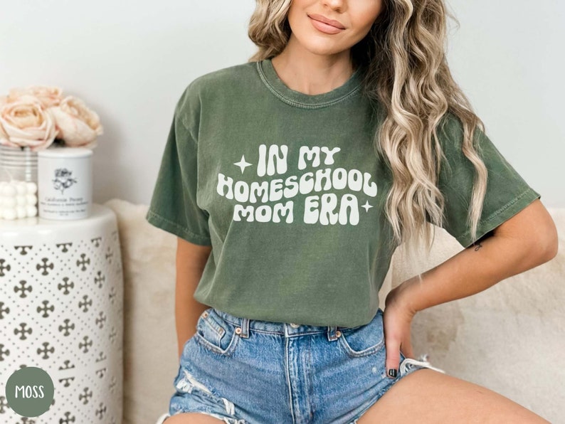 May include: A green t-shirt with the text "In My Homeschool Mom Era" in a retro font.