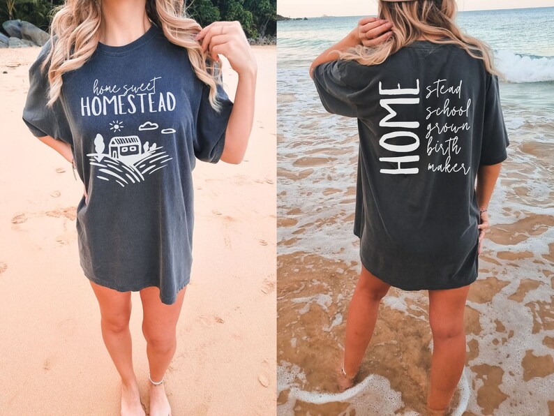May include: A dark gray t-shirt with a white graphic on the front that says "home sweet homestead" and a white graphic on the back that says "HOME" with the words "stead", "school", "grown", "birth", and "maker" stacked vertically below it.