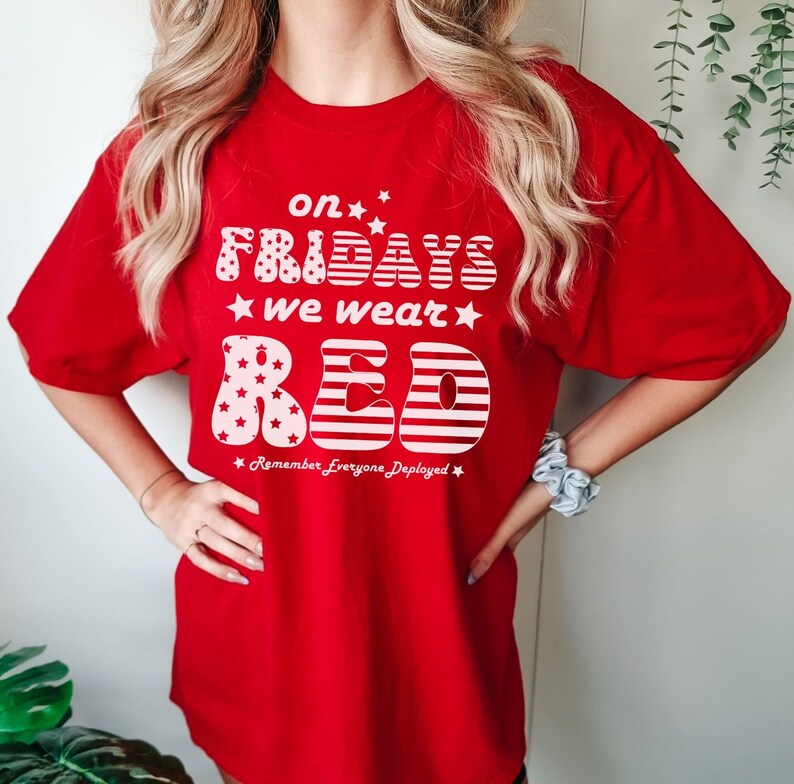Peut inclure: T-shirt rouge avec un motif blanc qui dit "On Fridays we wear red" avec des &eacute;toiles et un design de drapeau am&eacute;ricain. Le texte "Remember Everyone Deployed" est sous le graphique.