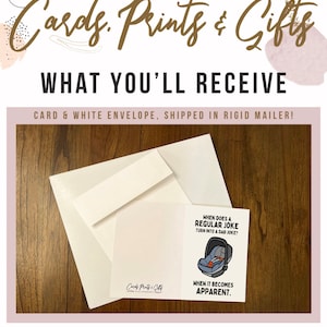 May include: A white card with a blue car seat illustration and the text "When does a regular joke turn into a dad joke? When it becomes apparent." The card is on a wooden surface with a white envelope.