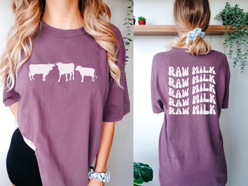 May include: A purple t-shirt with a graphic of three cows on the front and the text "RAW MILK" repeated five times on the back.