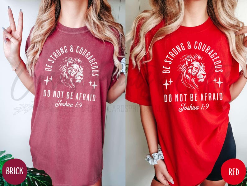 Pu&ograve; includere: Due t-shirt da donna con una grafica di un leone e il testo "Be Strong & Courageous Do Not Be Afraid Joshua 1:9". La maglietta a sinistra &egrave; rosso mattone e la maglietta a destra &egrave; rossa.