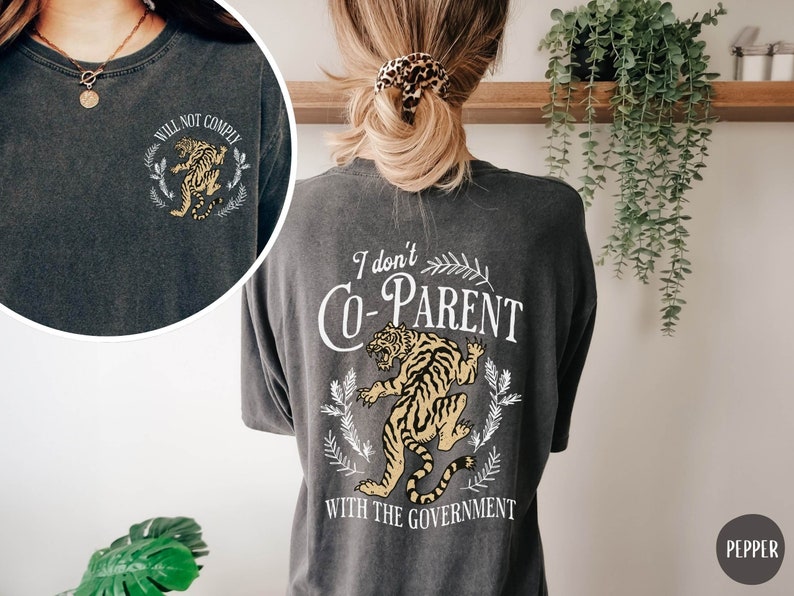 May include: A dark gray t-shirt with a tiger graphic and the text "I don't co-parent with the government".