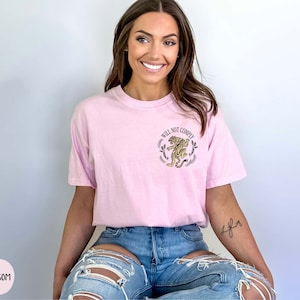 May include: A pink t-shirt with a graphic of a tiger and the text "Will Not Comply".