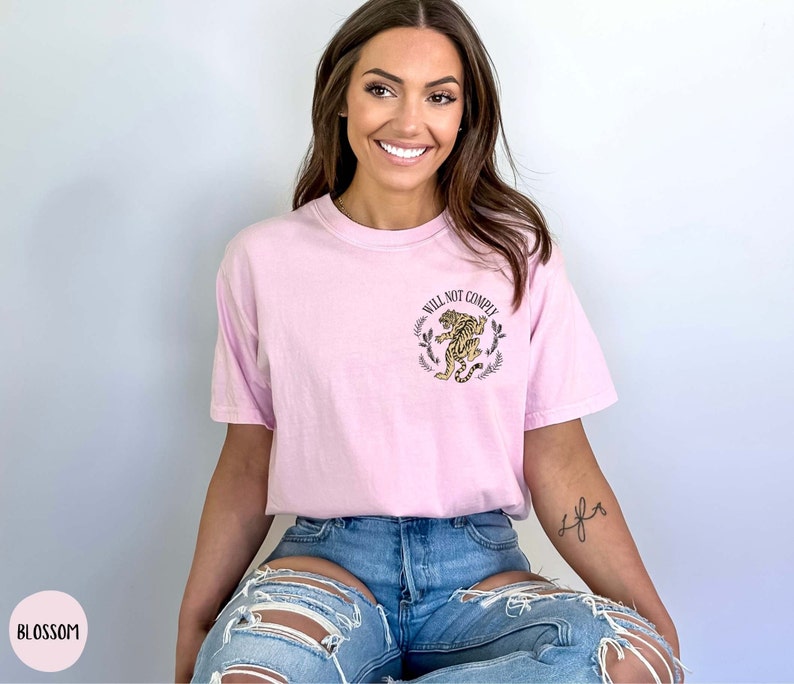 May include: A pink t-shirt with a graphic of a tiger and the text "Will Not Comply".