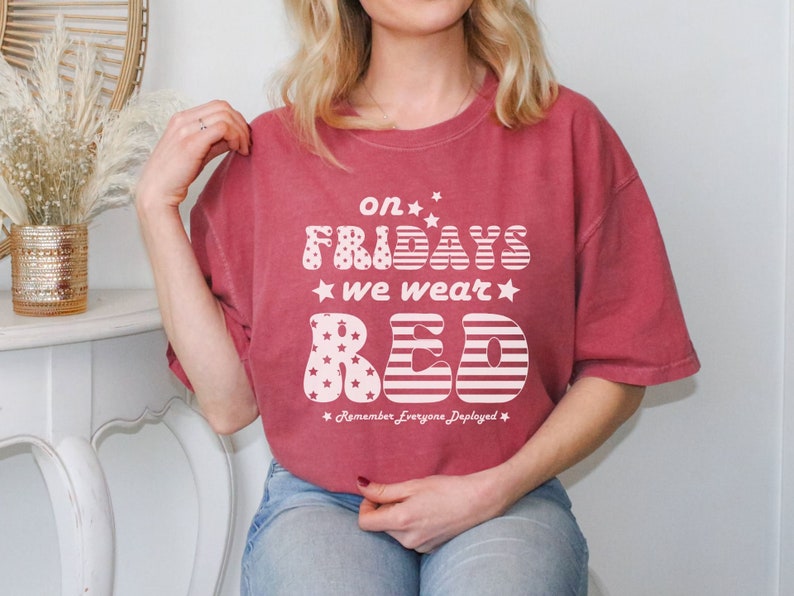 Peut inclure: T-shirt rouge, blanc et bleu avec l'inscription "on Fridays we wear red" et "Remember Everyone Deployed".