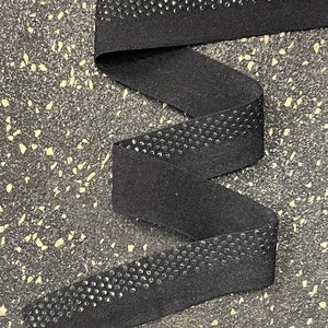 May include: Black elastic trim with a row of small, shiny black dots along the edge.