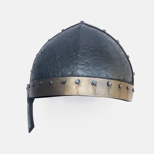 May include: A black helmet with a gold band and metal rivets. The helmet has a textured surface and a pointed top.