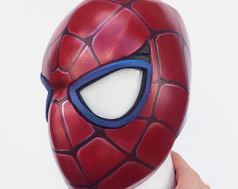 May include: A red and blue Spider-Man mask with a detailed web pattern. The mask has a white eye opening with a blue rim.