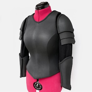 May include: Black leather armor with a padded chest piece and layered shoulder pads. The armor is displayed on a mannequin with a pink torso.
